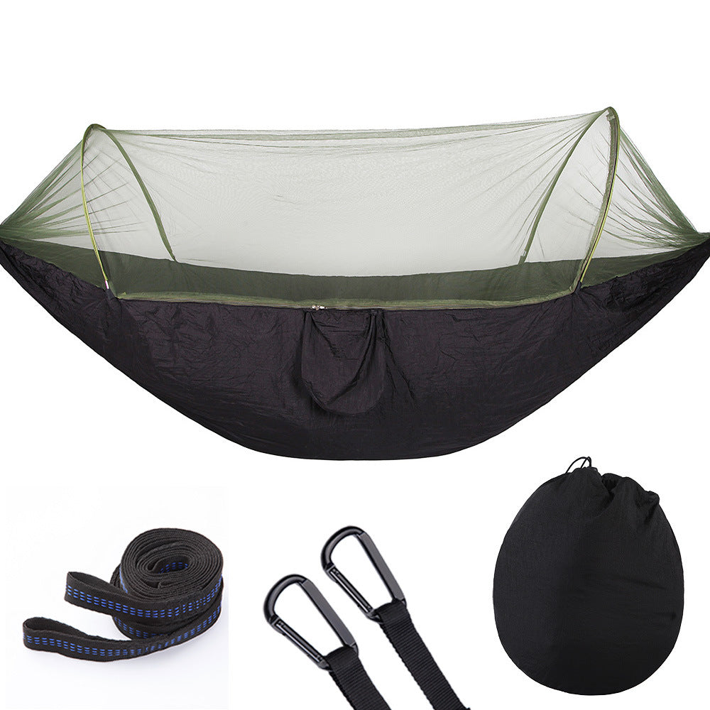 Two people sitting in a blue hammock with mosquito net in a forest setting